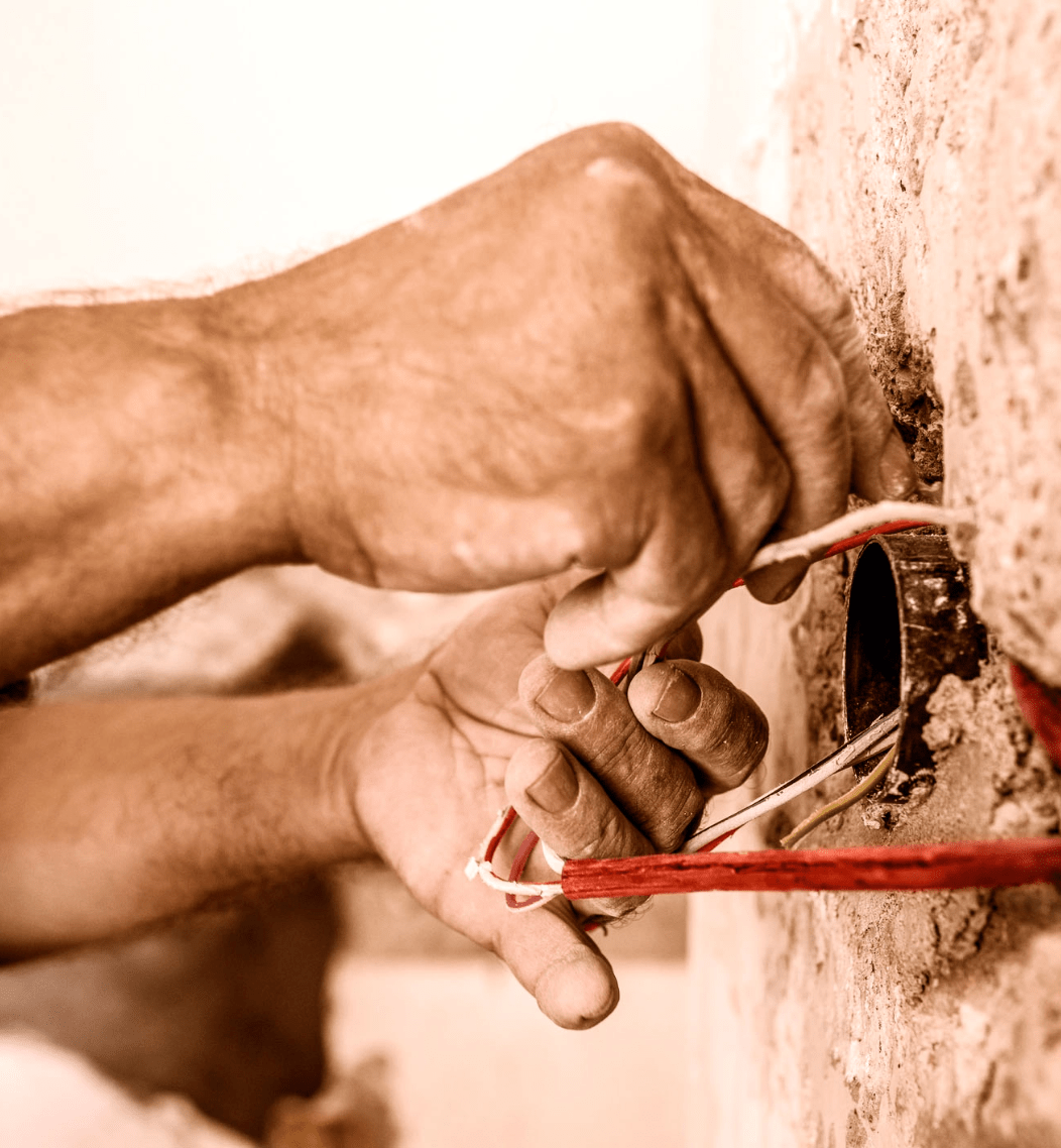 Handwerker Hände, die Kabel aus einem Mauervorsprung verdrahten